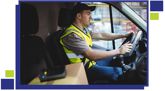 Delivery driver driving van with parcels on seat outside warehouse